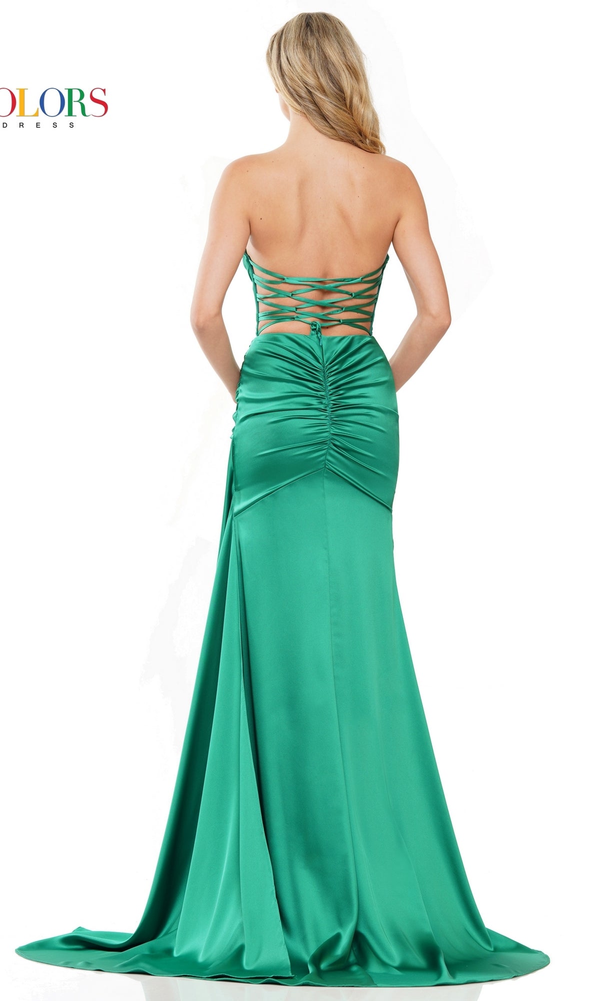 A woman stands with her back to the camera, wearing the Strappy-Back Strapless Long Satin Prom Dress 2968—an emerald green, floor-length gown featuring ruched detailing, a lace-up back, and an elegant formal silhouette.